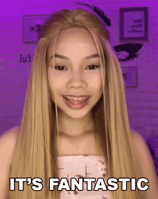 a woman with long blonde hair says it 's fantastic in front of a purple wall