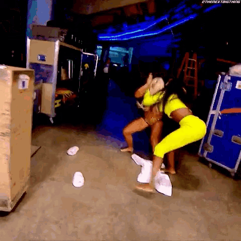 a couple of women are standing next to each other in a room . one of the women is wearing a neon yellow outfit .
