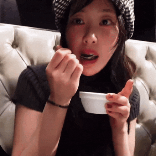 a woman sitting on a couch eating from a bowl