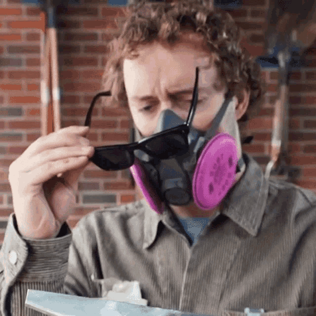 a man wearing a gas mask and sunglasses looks at something