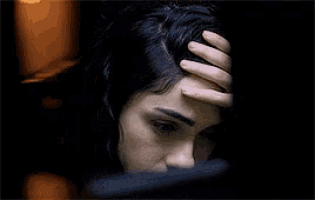 a close up of a woman 's face with a hand on her hair