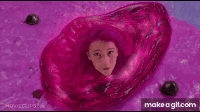 a girl with pink hair is floating in a pink liquid .
