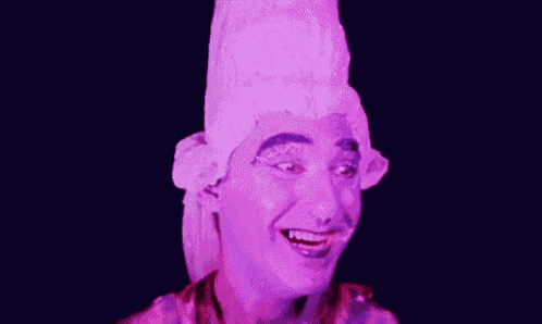 a man is wearing a purple wig and smiling in a purple light .