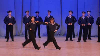 a group of men in navy uniforms are dancing on stage