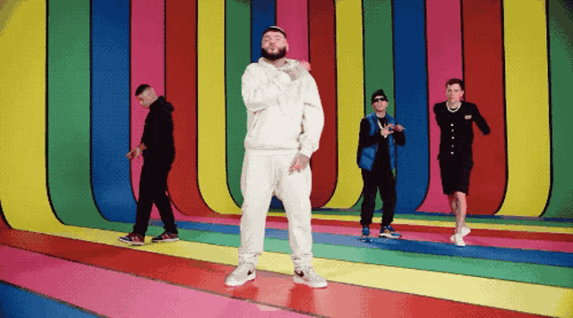 a group of young men are dancing in front of a colorful wall