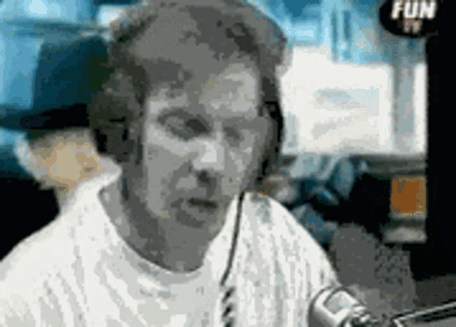 a man wearing headphones is sitting in front of a microphone with a fun tv logo in the background