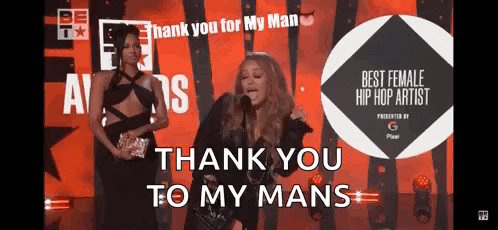 a woman is giving a speech on a stage and says " thank you to my mans "
