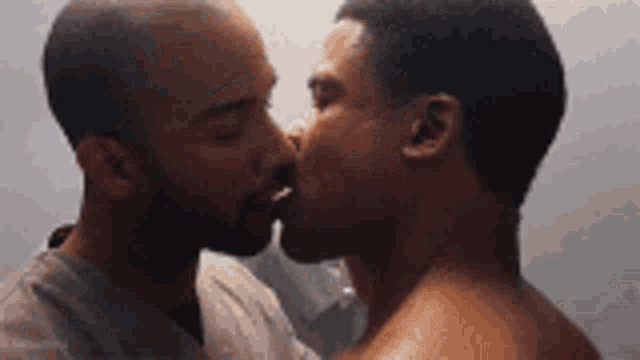 a couple of men are kissing each other in a bathroom .
