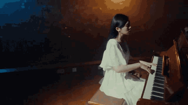 a woman in a white dress plays a piano