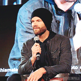 a man wearing a black hat is holding a microphone in front of a screen that says hiamata