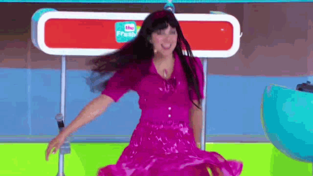 a woman in a pink dress is dancing in front of a microphone on a stage .