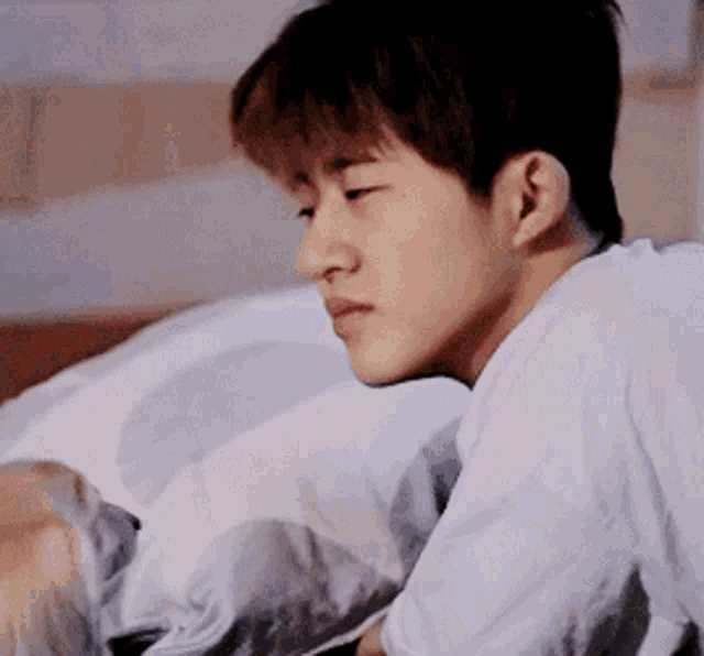 a man in a white shirt is laying in bed