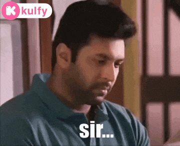 a man in a blue shirt is sitting in front of a window and saying sir .