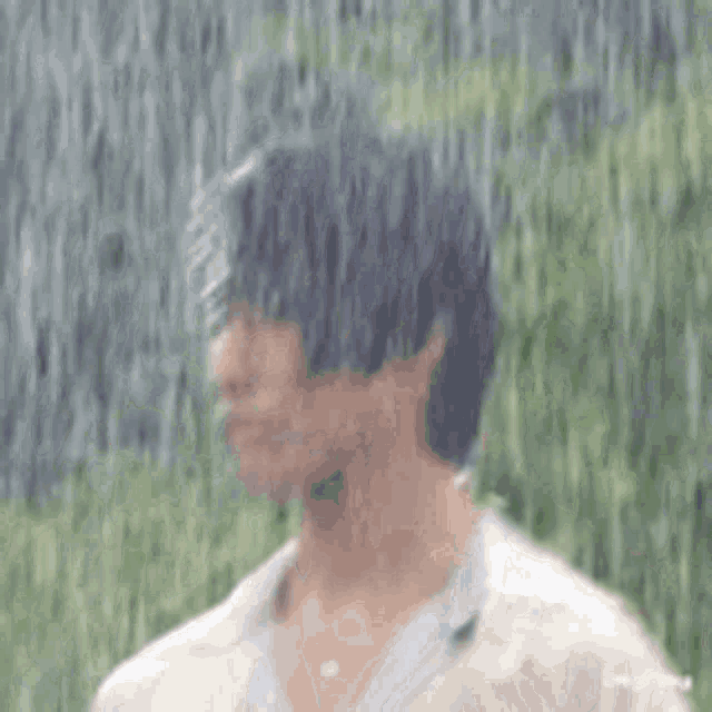 a man is standing in the rain looking at something .