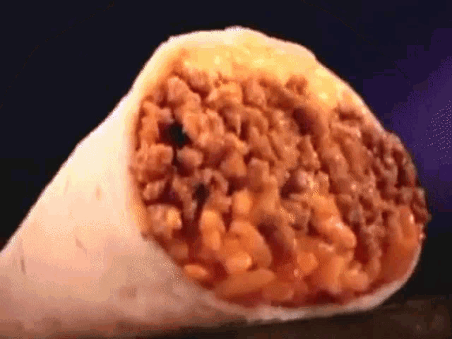 a burrito with meat and rice on a dark background