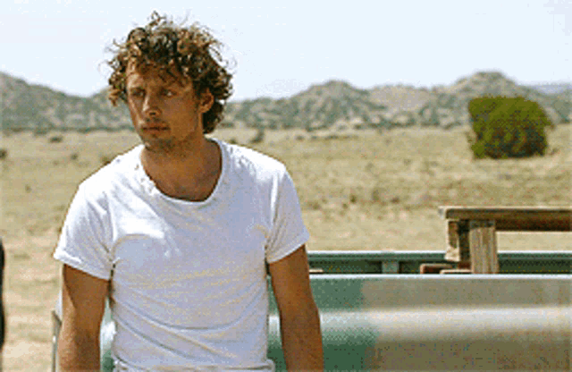 a man in a white shirt is sitting in a truck in the desert