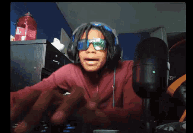 a person wearing headphones and sunglasses is standing in front of a microphone