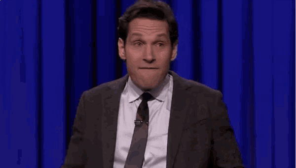 a man in a suit and tie is making a funny face with his mouth open .