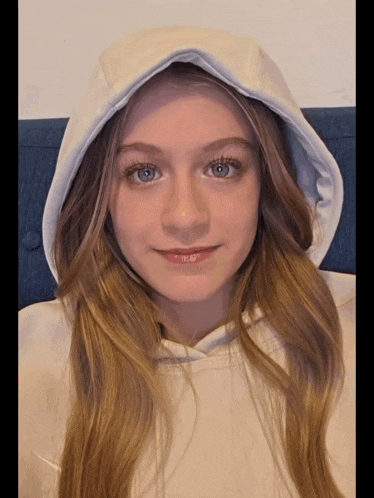 a young girl wearing a white hoodie with a hood on her head