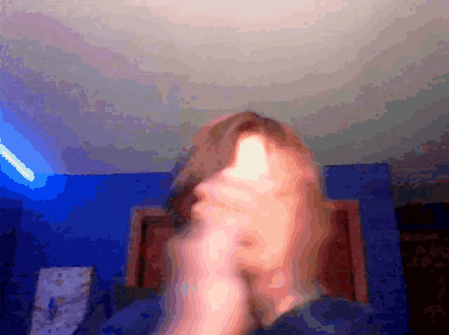 a blurry picture of a person 's face with a blue wall in the background