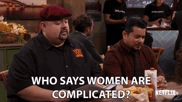 two men are sitting at a table with the words who says women are complicated