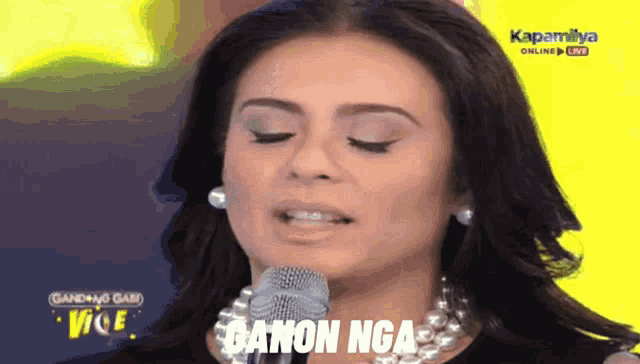 a woman singing into a microphone with the words canon nga on the bottom