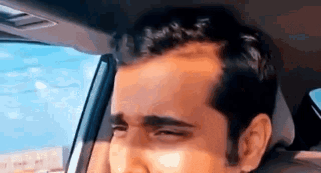a man is sitting in the back seat of a car and making a funny face .