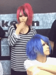 a woman with red hair and a blue wig is standing next to a woman with blue hair .