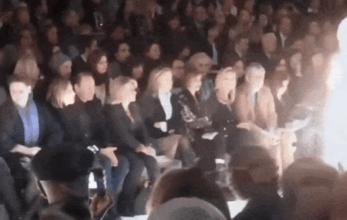 a group of people are sitting in a row at a fashion show