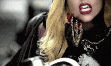 a close up of a woman 's mouth with red lipstick and chains around her neck