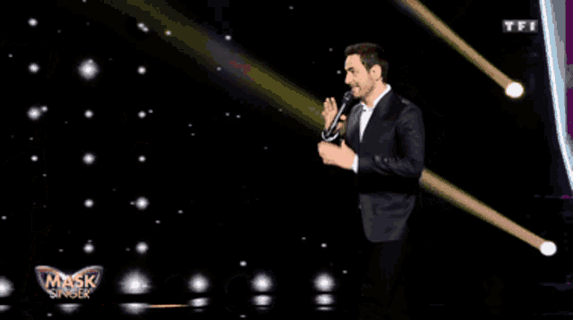 a man in a suit is standing in front of a mask singer costume