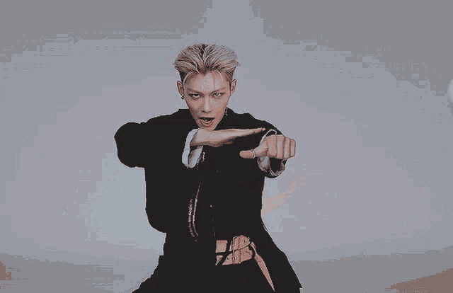 a man in a black jacket is pointing his finger at the camera