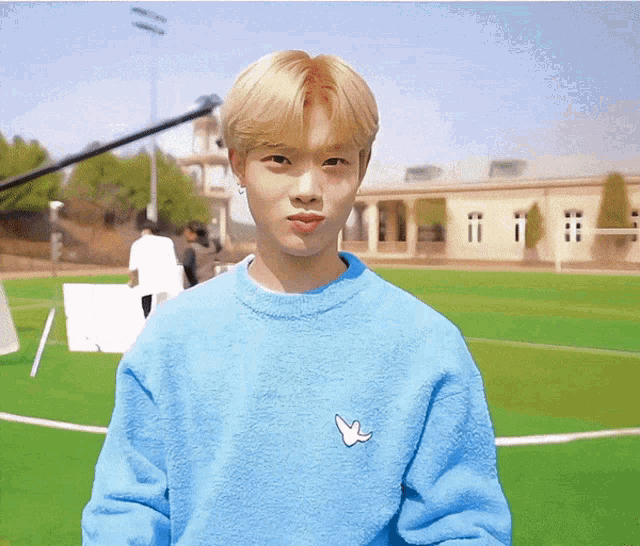 a young man wearing a blue sweater with a white bird on the chest