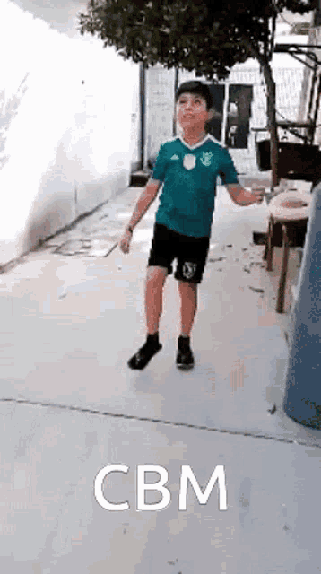 a young boy in a green shirt and black shorts is jumping a rope .