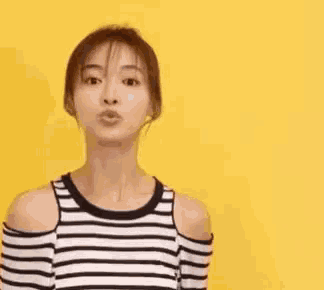 a woman in a striped shirt is laughing in front of a yellow wall .