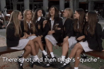 a group of girls in school uniforms are sitting on a bench and talking .