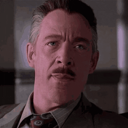 a man in a suit and tie looks at the camera