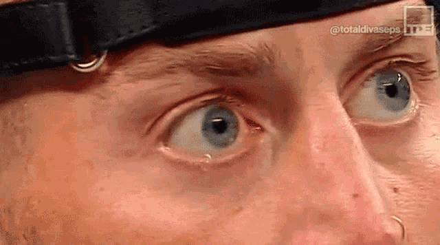 a close up of a man 's blue eyes wearing a black hat .