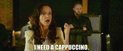 a woman is saying i need a cappuccino while a man stands behind her .