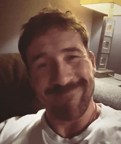 a man with a beard wearing a white shirt smiles for the camera