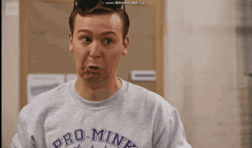 a man wearing a grey shirt that says pro mini makes a funny face
