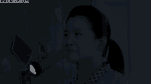 a woman is holding a flashlight in a dark room with the website kagaya.com in the background
