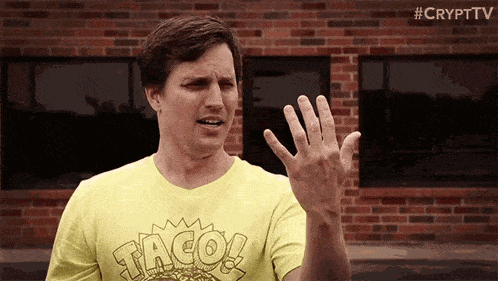 a man wearing a yellow taco t-shirt is making a funny face .