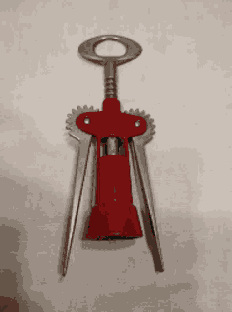 a red corkscrew with a silver handle on a white cloth