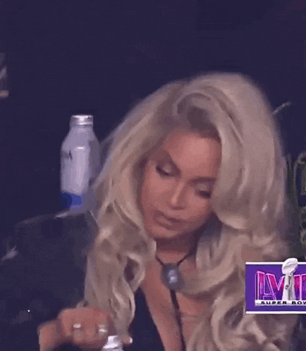 a woman with blonde hair is sitting in front of a sign that says super bowl lvi .