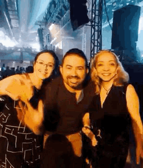a man and two women are posing for a picture in front of a crowd at a concert .