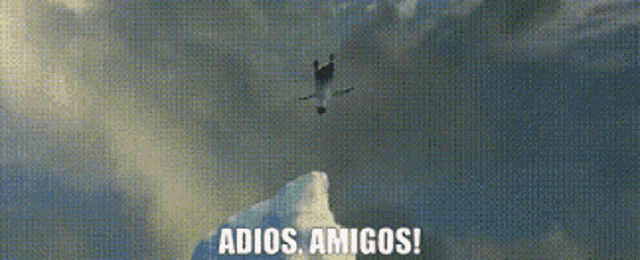 a man is standing on top of a snow covered mountain with the words `` adios amigos '' written on it .