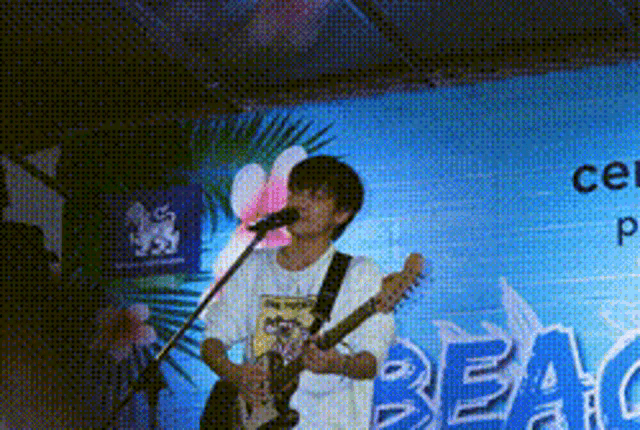 a man is singing into a microphone while playing a guitar