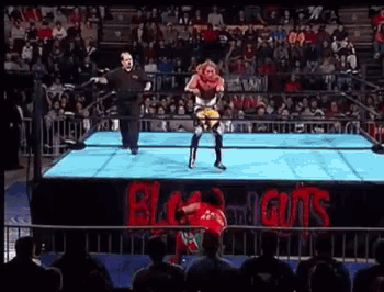 a wrestling match is taking place in a stadium with a sign that says black guts