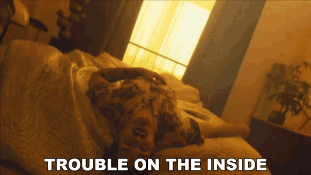 a man is laying on a bed with the words trouble on the inside behind him